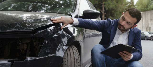 Car Accident Lawyer Inspecting Damage to a Car
