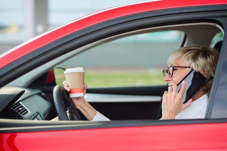 Distracted driver talks on cell phone and holds coffee