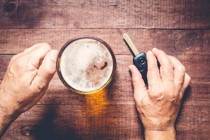 Man holds beer and considers drinking and driving