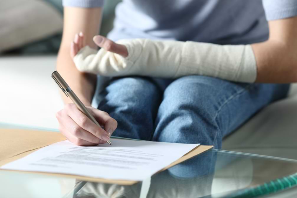 woman with bandaged arm signing medical care document after being hurt