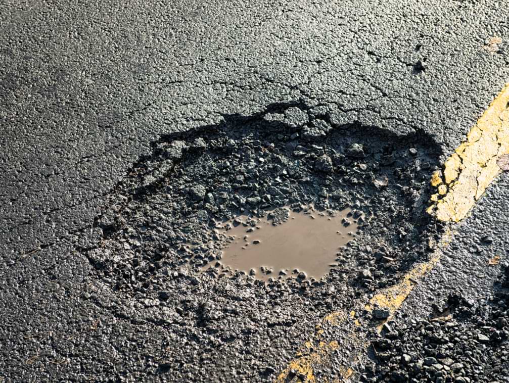Close-up of a deep pothole causing a danger of car accidents to drivers