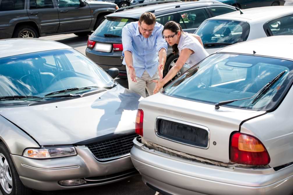 Two drivers arguing in front of cars after having a parking lot accident