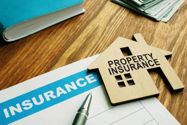 Property insurance form with a wooden cutout of a home on top of the form for property damage