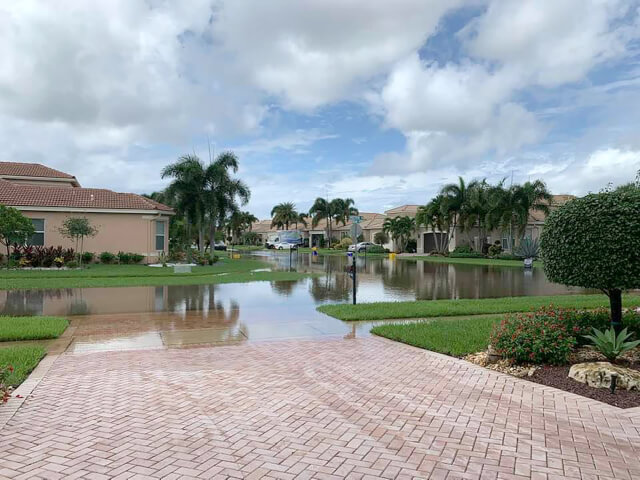 Street and driveway in a suburban residential community property damaged flooded from a rainstorm in Florida Oakland Park Hurricane & Property Damage Lawyers