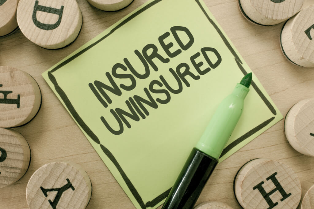 letter blocks surrounding note saying Insured Uninsured under a pen