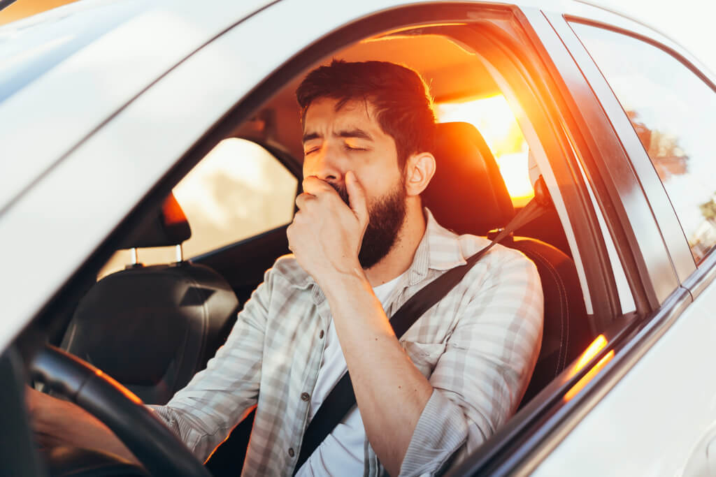 Tired man yawning while driving his car Fatigued