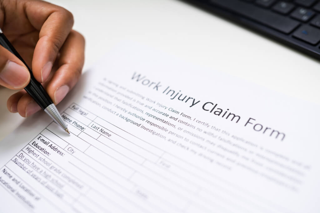 A hand filling out workers compensation injury form