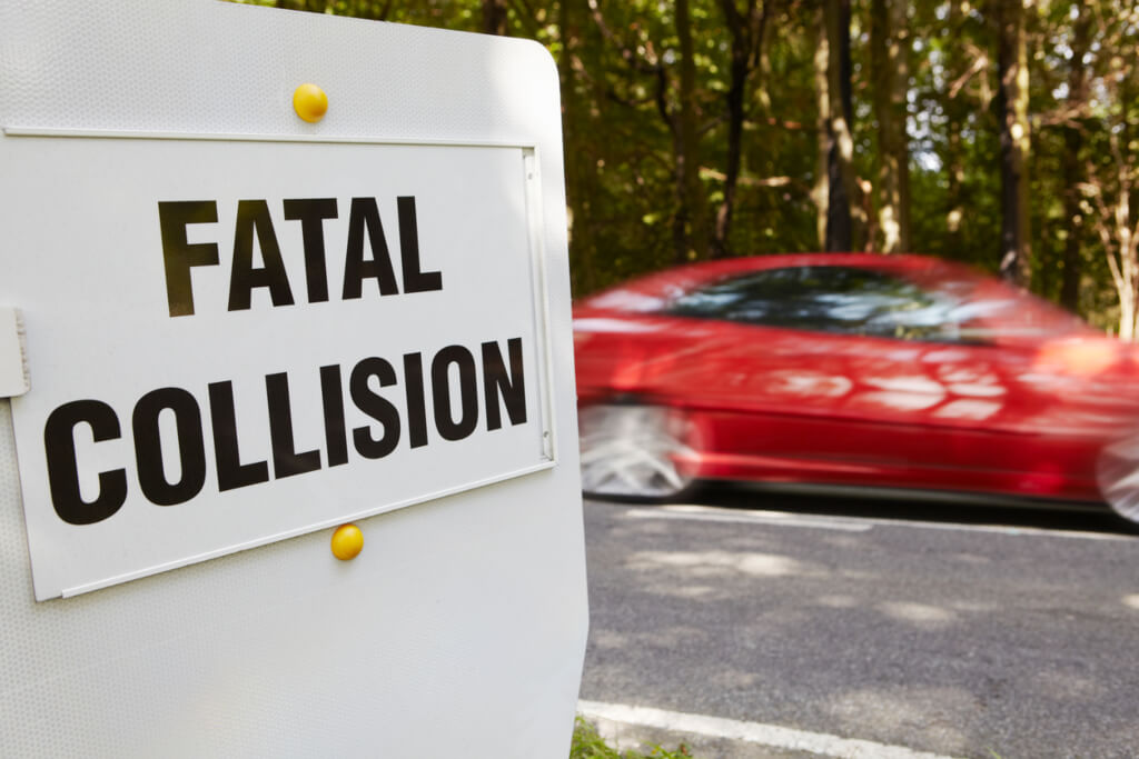 Blurier car passing by a sign saying fatal collision