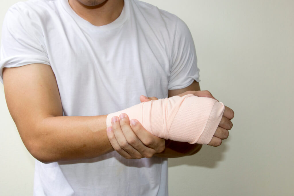 Man holding bandaged hand and wrist from repetitive stress injury