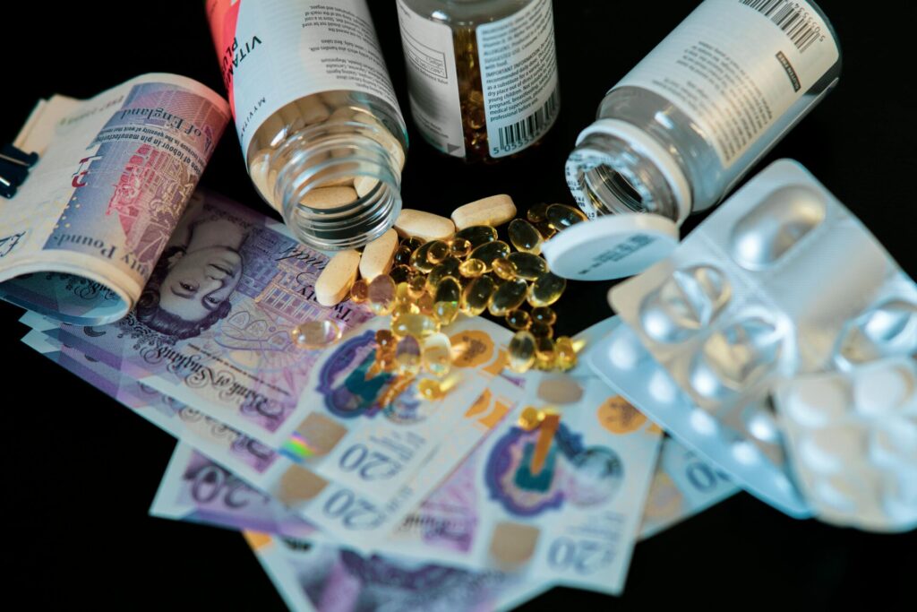 A still life of supplements, pills, and currency with a dark backdrop.